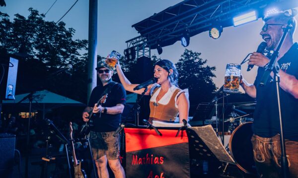 Band mit Bierkrug beim Prosit der Gemütlichkeit im Biergarten vor Sonnenuntergang